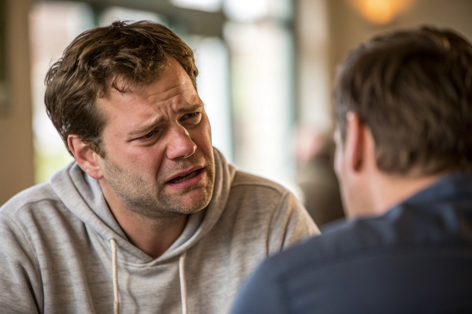 Man tijdens gespannen gesprek, fysiologische stress zichtbaar