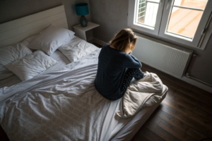Beeld bij twijfels over je relatie: one adult woman sitting on the edge of an unmade bed