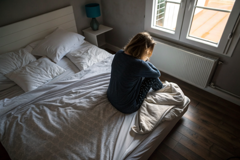 Beeld bij twijfels over je relatie: one adult woman sitting on the edge of an unmade bed