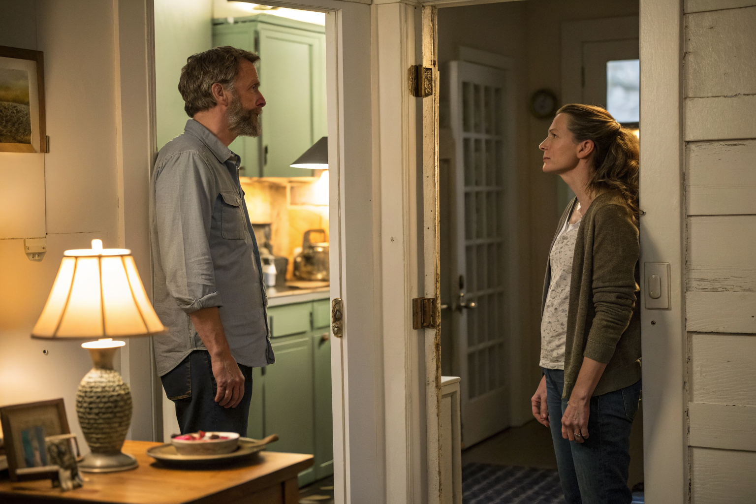 Beeld bij one adult man and one adult woman standing apart in a kitchen doorway