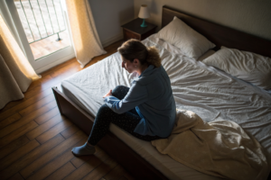 Beeld bij twijfels over je relatie: one adult woman sitting on the edge of an unmade bed