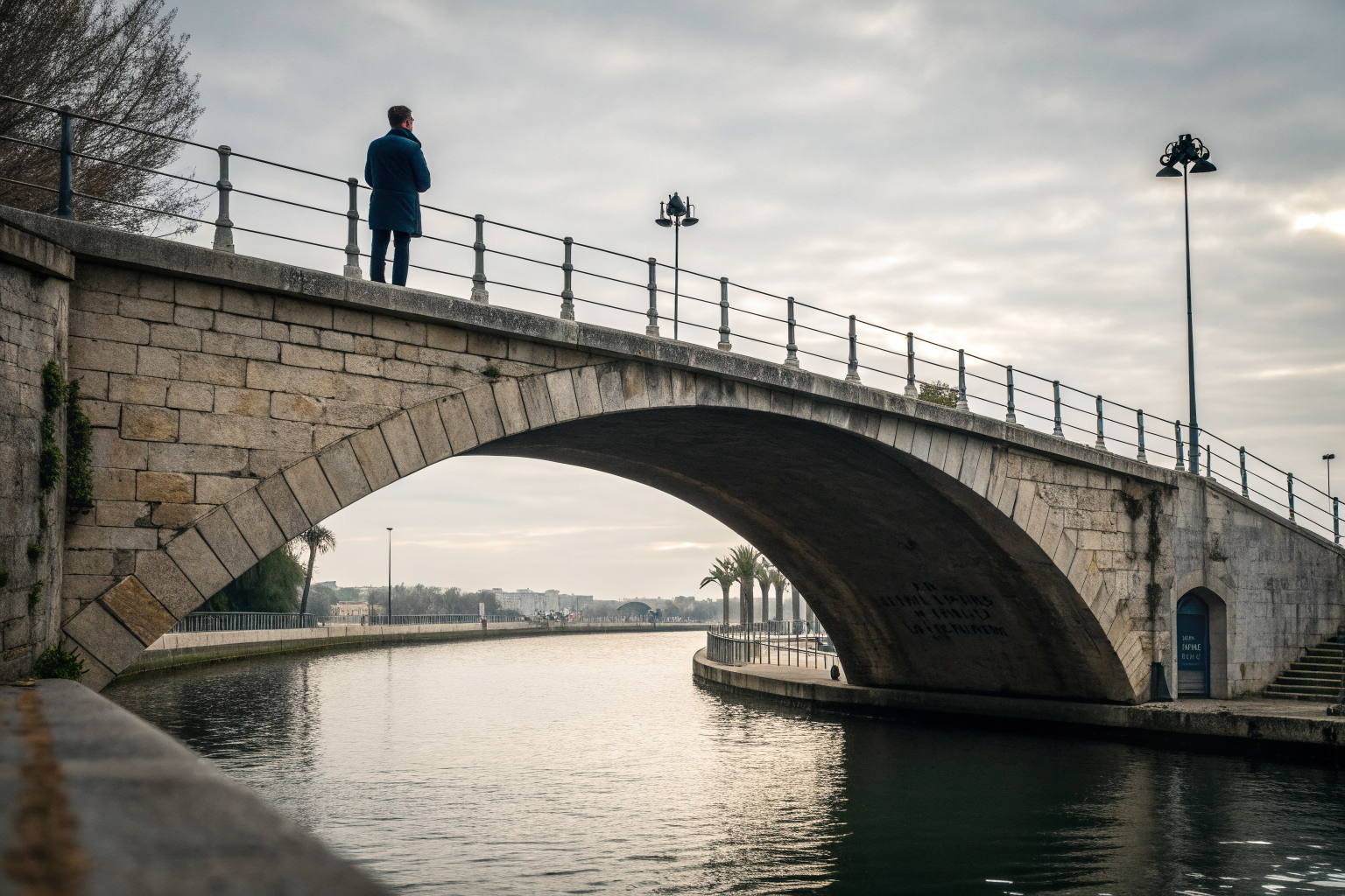 Iemand staat peinzend op een boogbrug boven rustig water, nadenken over je partner werkelijk begrijpen